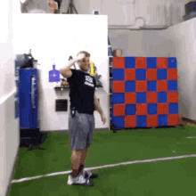 a man wearing a black shirt that says ' iowa ' on it salutes in front of a checkerboard wall