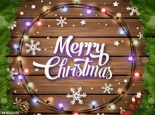 a wooden background with christmas lights and snowflakes and the words merry christmas