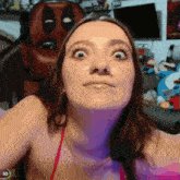 a woman is making a funny face in front of a deadpool statue