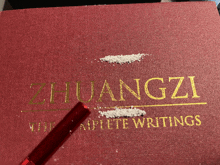 a red book titled huangzi complete writings with a red pen on top