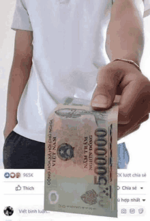 a man is holding a stack of money in his hand .