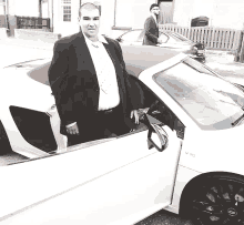 a man in a suit is standing next to a white sports car that says v10