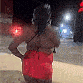 a woman in a red dress is standing on the side of the road .