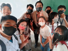 a group of students wearing face masks pose for a picture with a man wearing a black mask