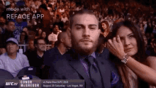 a man in a suit and tie is sitting next to a woman in a crowd at a ufc fight .