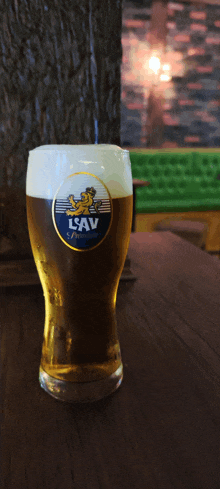 a glass of lsav beer is sitting on a wooden table