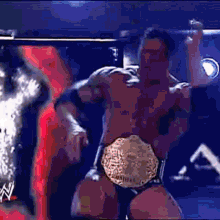 a man in a wrestling ring is wearing a world heavyweight championship belt ..