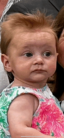 a baby with red hair is wearing a pink and white dress