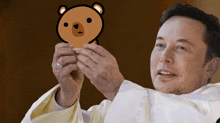 a man in a white robe holds a teddy bear in front of his face