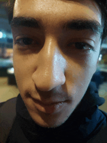 a close up of a young man 's face with a black shirt on