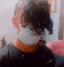 a close up of a person wearing a face mask with their hair in a bun .