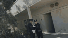 two police officers shaking hands in front of a building with a sign that says ' emergency ' on it