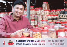 a man in a red shirt stands in front of jars of food with the name andrew chen kah eng on the bottom