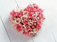 a heart made of pink and white roses on a white surface