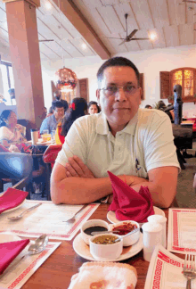 a man sits at a table in a restaurant with a red napkin and a plate of food