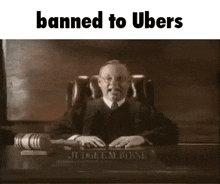 a judge is sitting at a table with a gavel in front of him and the words `` banned to ubers '' .