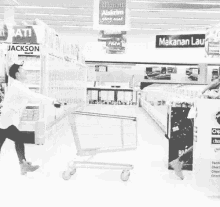 a black and white photo of a man pushing a shopping cart in a store with a sign above him that says jackson