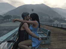 a man and a woman are kissing on a pier