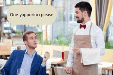 a man in a suit is talking to a waiter in an apron in a restaurant .