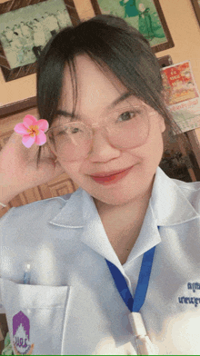 a woman wearing glasses and a white shirt has a flower in her hand