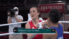 a woman in a red adidas shirt is fighting another woman in a blue shirt in a boxing ring at tokyo 2020