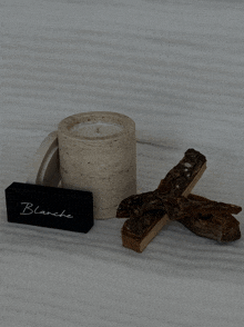 a candle sits next to a wooden stick and a black box that says blanche