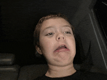 a young boy is making a funny face in the back seat of a car