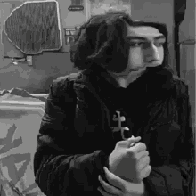 a black and white photo of a young man holding a cross