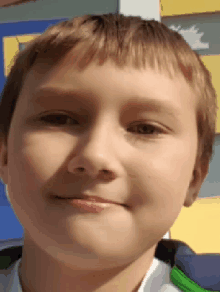 a close up of a young boy 's face with a green jacket on