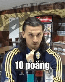 a man with long hair is sitting in a restaurant with a bottle of water in his hand .