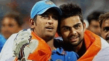 two cricket players are posing for a picture together on a stadium .