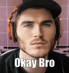 a man wearing headphones and a hat with the words `` okay bro '' written on his face .