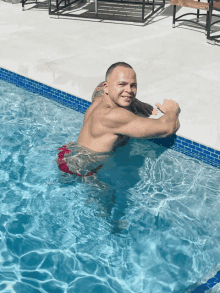 a shirtless man in a red swim trunk is in a swimming pool