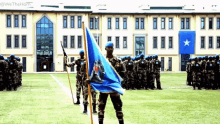 a group of soldiers are standing in front of a building with a blue flag and a star on it