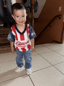 a little boy wearing a red white and blue caliente shirt