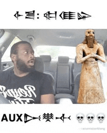 a man is sitting in the back seat of a car next to a statue of a man with a beard .