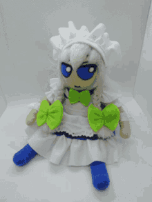 a stuffed doll with white hair and blue eyes has green bows around her waist