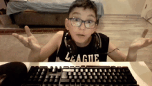 a boy wearing headphones and a shirt that says league sits in front of a keyboard