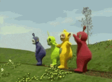 a group of teletubbies are standing in a field .