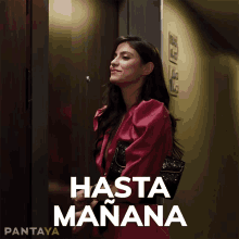 a woman in a red dress is standing in an elevator with hasta manana written on the bottom right