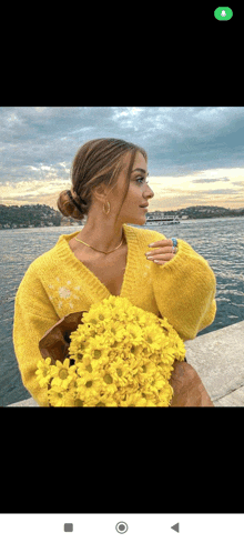 a woman in a yellow sweater holding a bouquet of yellow flowers