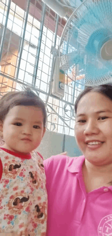 a woman in a pink shirt is holding a little girl