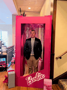 a man in a suit and tie is standing in a pink barbie box