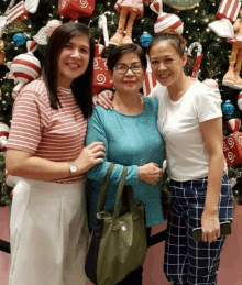 three women pose in front of a christmas tree