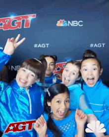 a group of young girls are posing for a photo in front of a sign that says agt on it