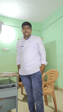 a man with his hands in his pockets stands in front of a chair