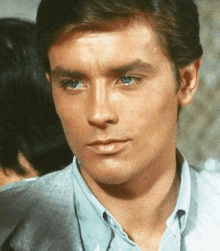 a close up of a man 's face with blue eyes and a blue shirt