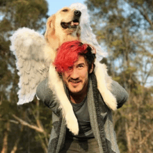 a man with red hair is carrying a dog with angel wings