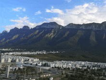 a city with mountains in the background and a few houses in the foreground