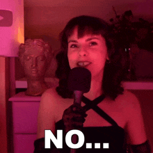 a woman in a black dress is holding a microphone and says " no "